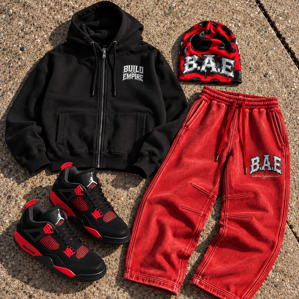 Black B.A.E. Build An Empire hoodie, red vintage wash sweatpants, red and black cow print beanie and black red sneakers styled together in a realistic urban streetwear flat lay.