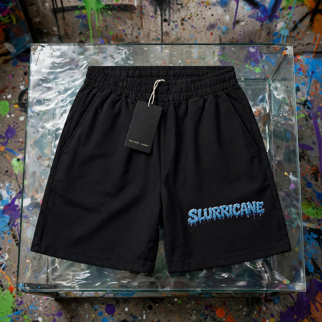 Black Slurricane boxy shorts flat lay on glass display table with hang tag - 240 GSM unisex streetwear shorts with icy blue drippy logo - ZAZA Reserve collection by Millions Pending