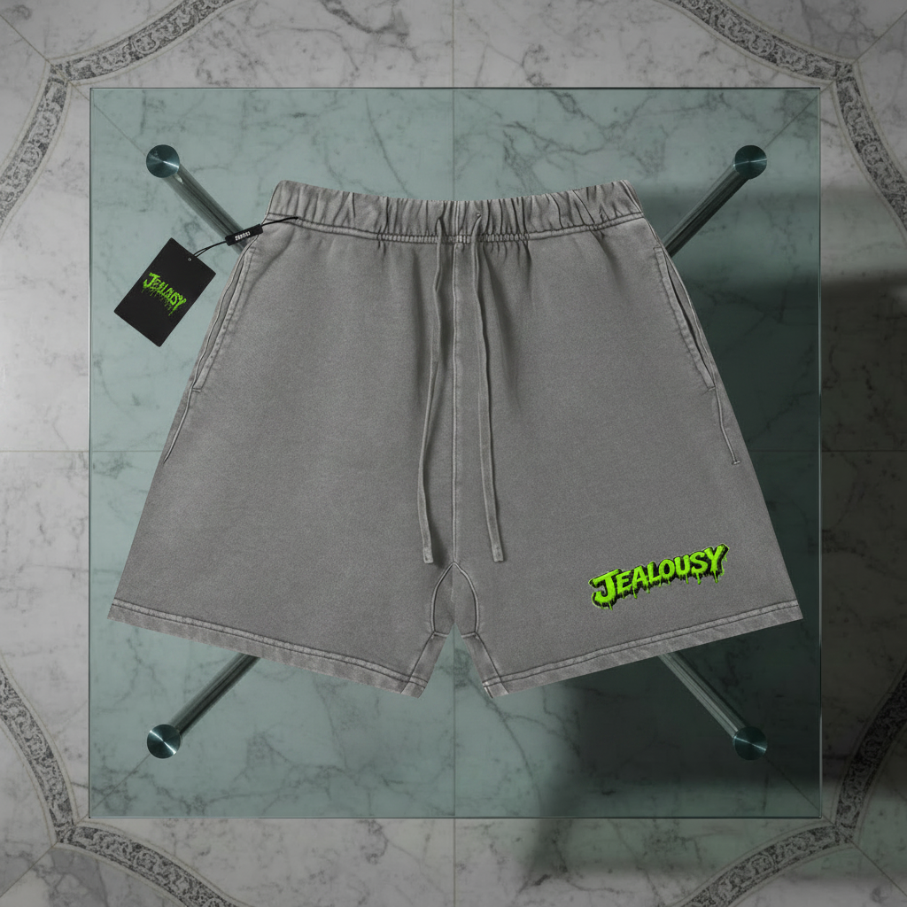 Jealousy cannabis strain shorts flat lay summer fashion, grey heavyweight 360gsm vintage wash boxy mid waist above knee skateboard shorts with green slime left leg logo, men’s skateboarder summer shorts streetwear trending, smoke shop dispensary apparel, premium cotton shorts flat lay NFEO ZAZA RESERVE wear your favorite strains