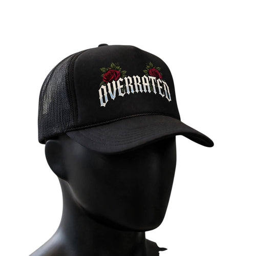 OVERRATED Premium Foam Rope Trucker Hat: Black OVERRATED premium foam rope trucker hat with breathable mesh back, curved brim, and embroidered-style OVERRATED graphic with red rose accents, displayed on a clean white background.